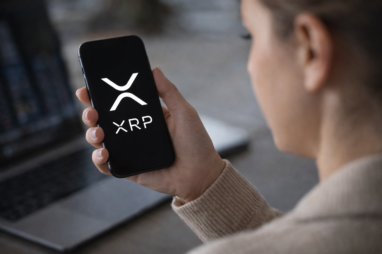 Person holding a smartphone displaying the XRP cryptocurrency logo while checking digital asset markets.